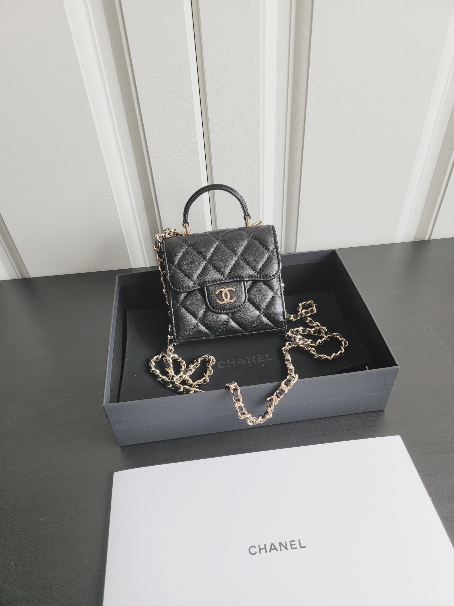 23P Mini Classic Flap Bag with Top Handle in Black Quilted Caviar Leather with Light Gold-Tone Hardware