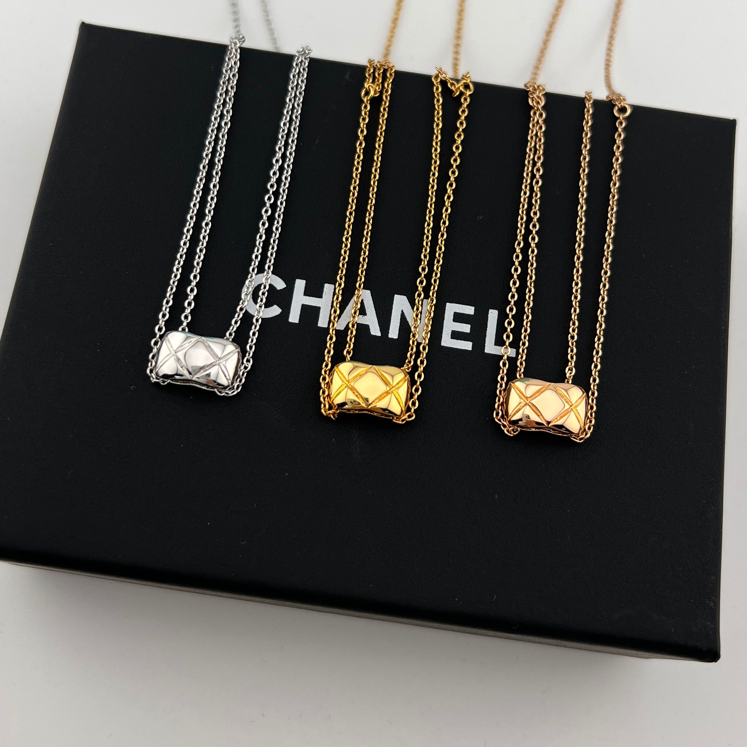 Two-layer necklace with two vegetable-patterned pendants on a smooth surface