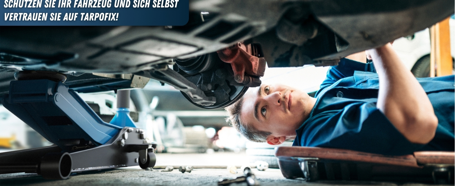 Blick von unten auf ein Fahrzeug auf einer Hebeb&uuml;hne, das mechanische Arbeiten am Unterboden zeigt.